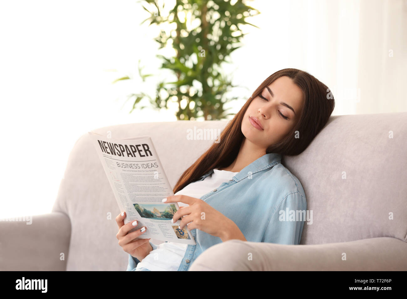 Junge Frau liest Zeitung im Innenbereich Stockfoto