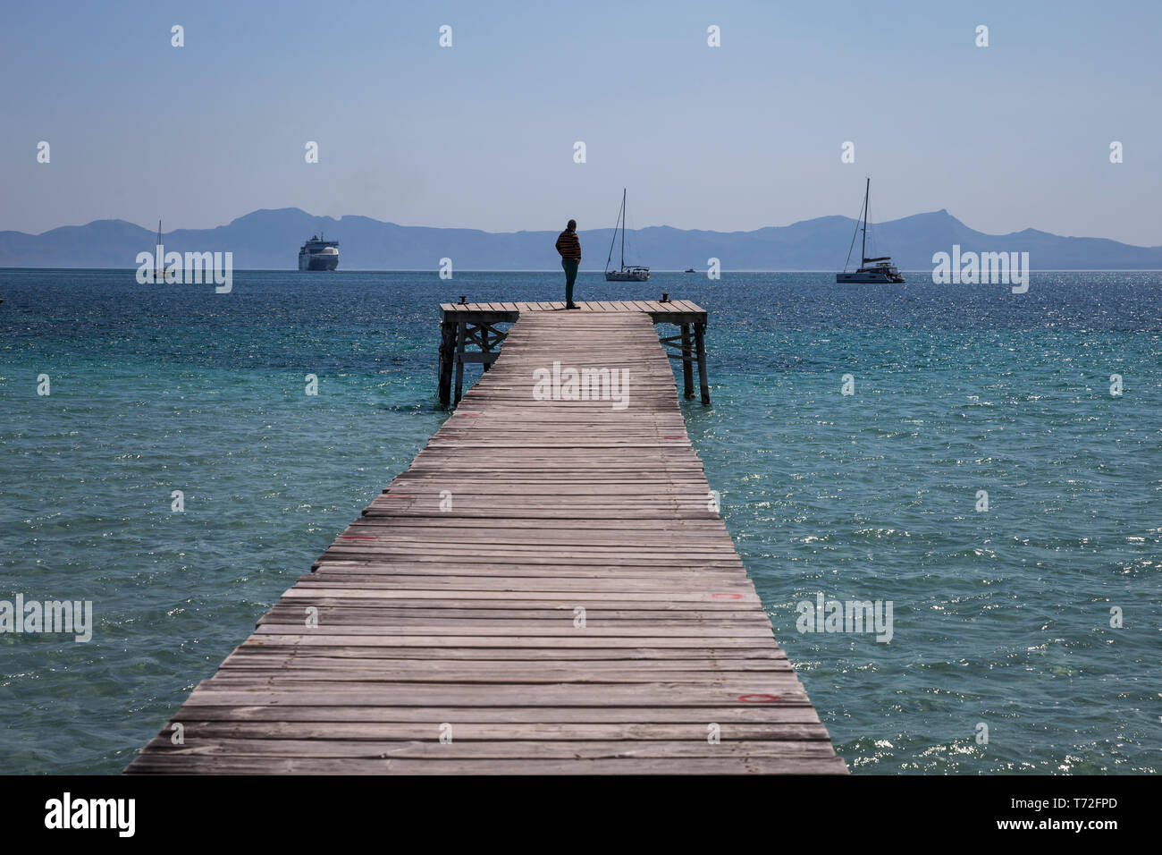 Ein Mann steht auf einem Holzsteg in Port d'Alcudia, Mallorca, Spanien. Stockfoto