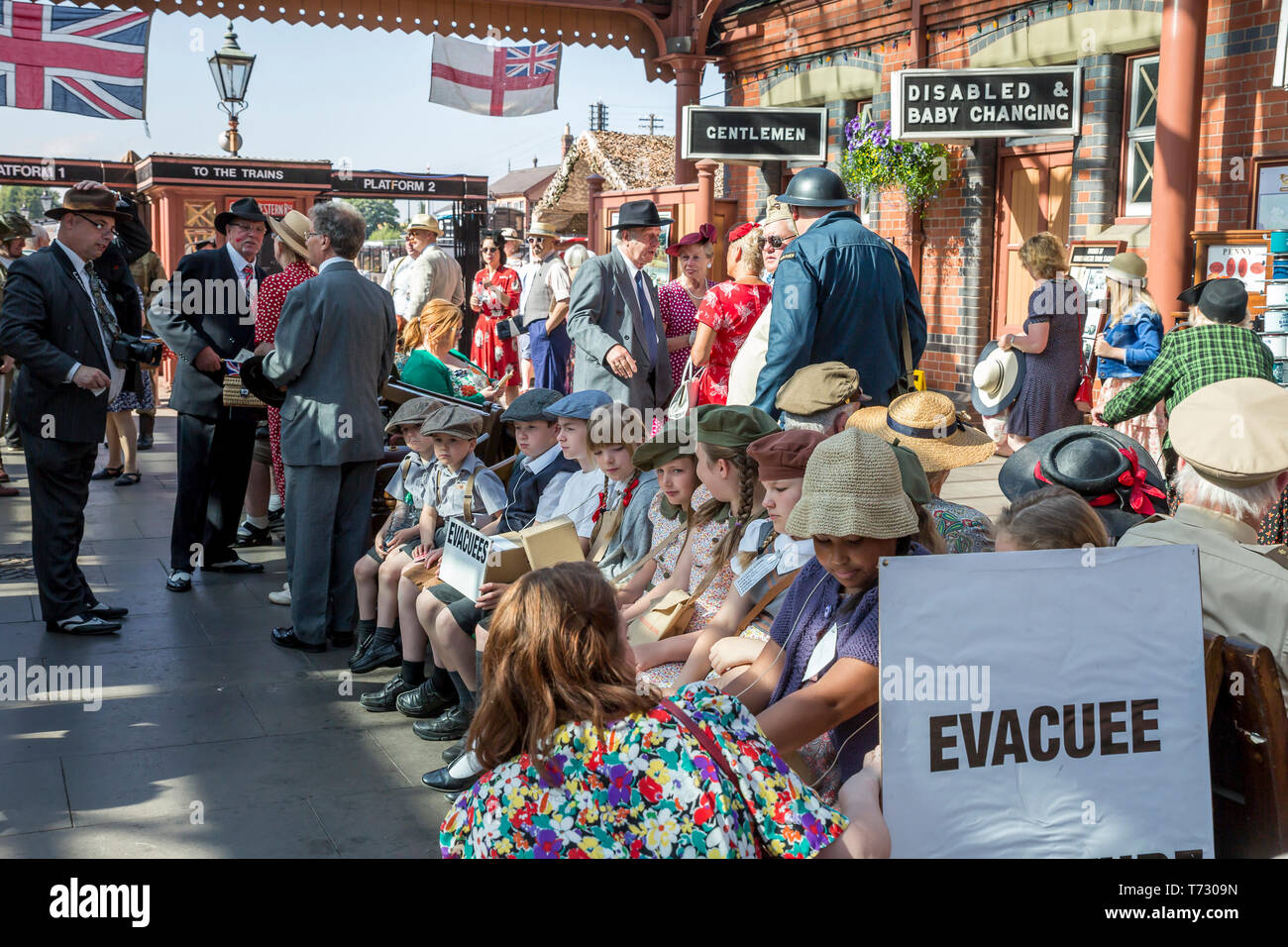 Die Severn Valley Railway, 1940 der Kriegszeit Ereignis, Kidderminster Vintage Railway Station. Jungen & Mädchen (EVAKUIERTEN) im Jahre 1940 die Kleid sitzt auf der Bank warten. Stockfoto