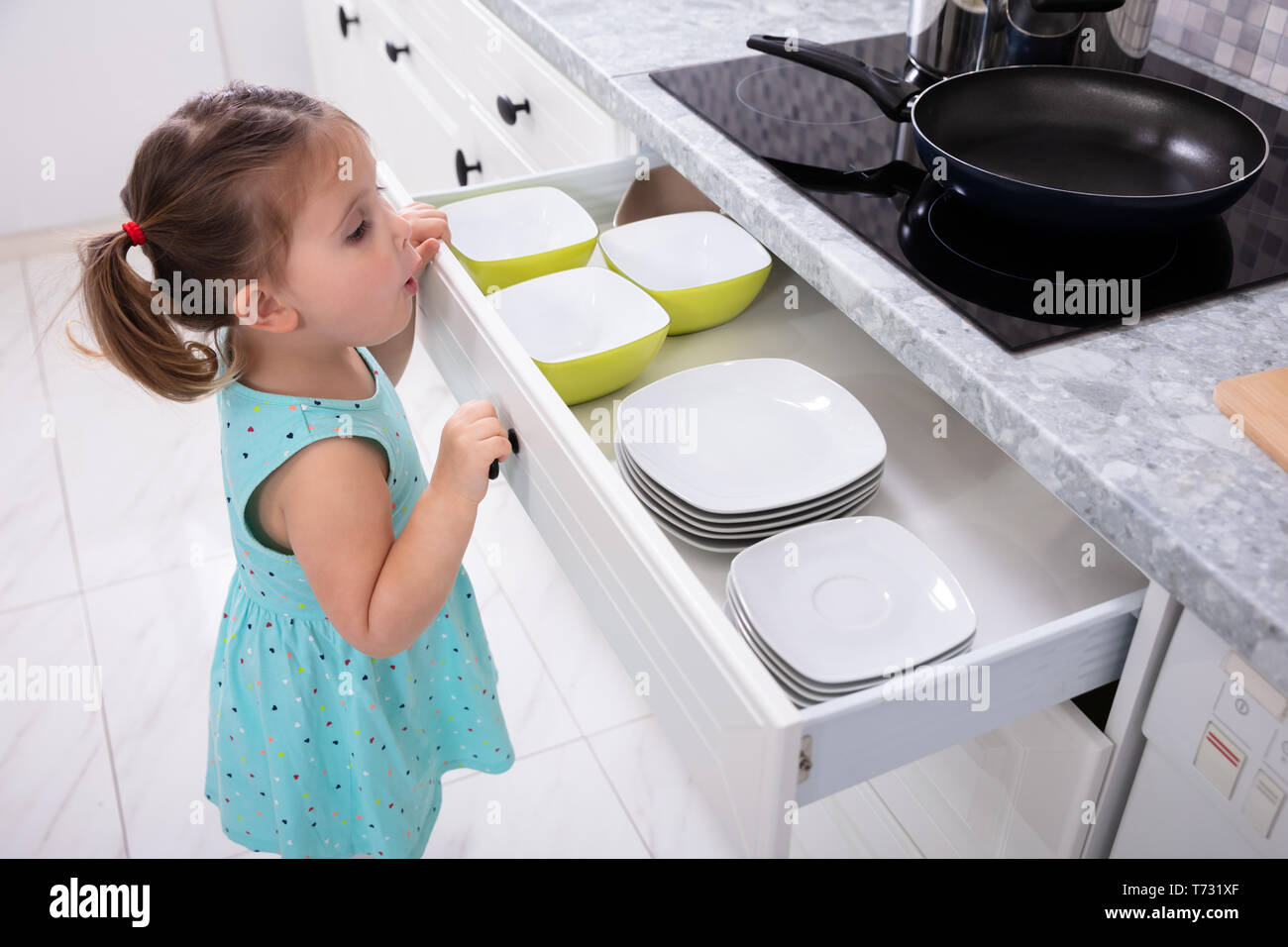 Seitenansicht des kleinen Mädchens öffnen die Küche Schublade Stockfoto