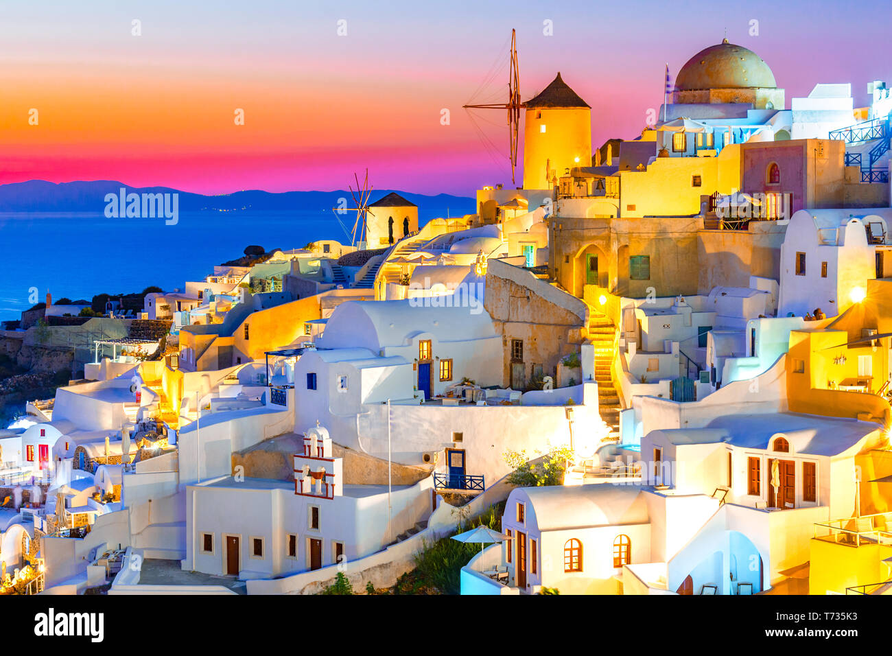 Sonnenuntergang in Oia, Santorini, Griechenland bei Sonnenuntergang. Traditionelle und berühmte weisse Häuser und Kirchen mit blauen Kuppeln auf die Caldera, Ägäis. Stockfoto