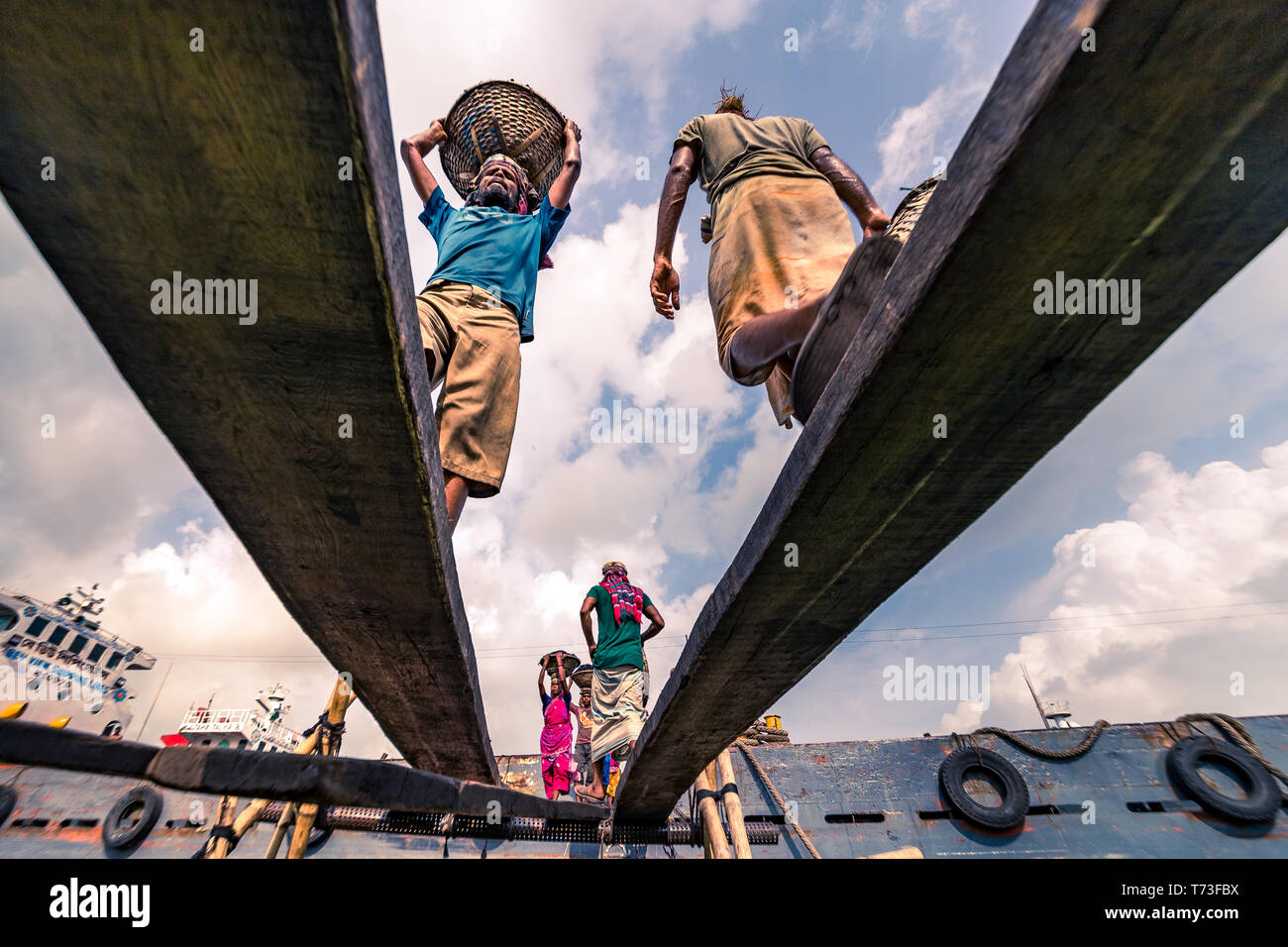 Männliche & Weibliche Hafenarbeiter werden gesehen, wie sie Kohle mit Bambus Körbe von Fähren an buriganga Flusshafen in Dhaka, Bangladesch entladen. Stockfoto