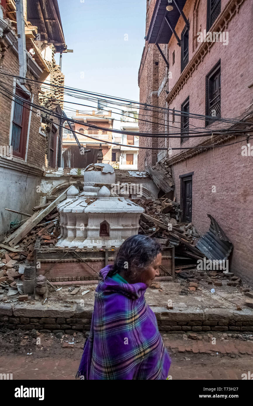 Eine ältere Frau Spaziergänge hinter den Trümmern der Tempel, fiel bei einem großen Erdbeben, in Bhaktapur Durbar Square in Kathmandu Tal, das ein Uneso Stockfoto