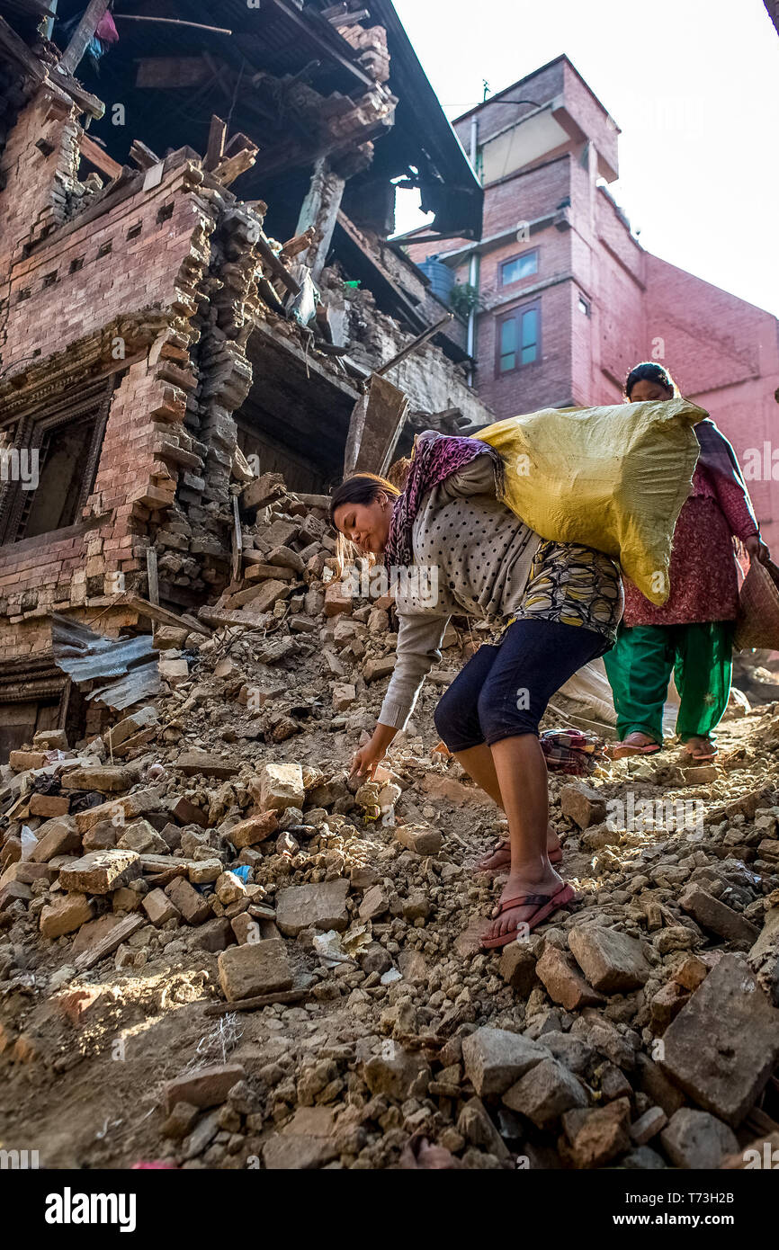 Die überlebenden mit ihren Habseligkeiten klettern Sie einen Damm der Schutt von einem gefallenen Gebäude, in Bhaktapur Durbar Square in Kathmandu Tal, das ein unes Stockfoto