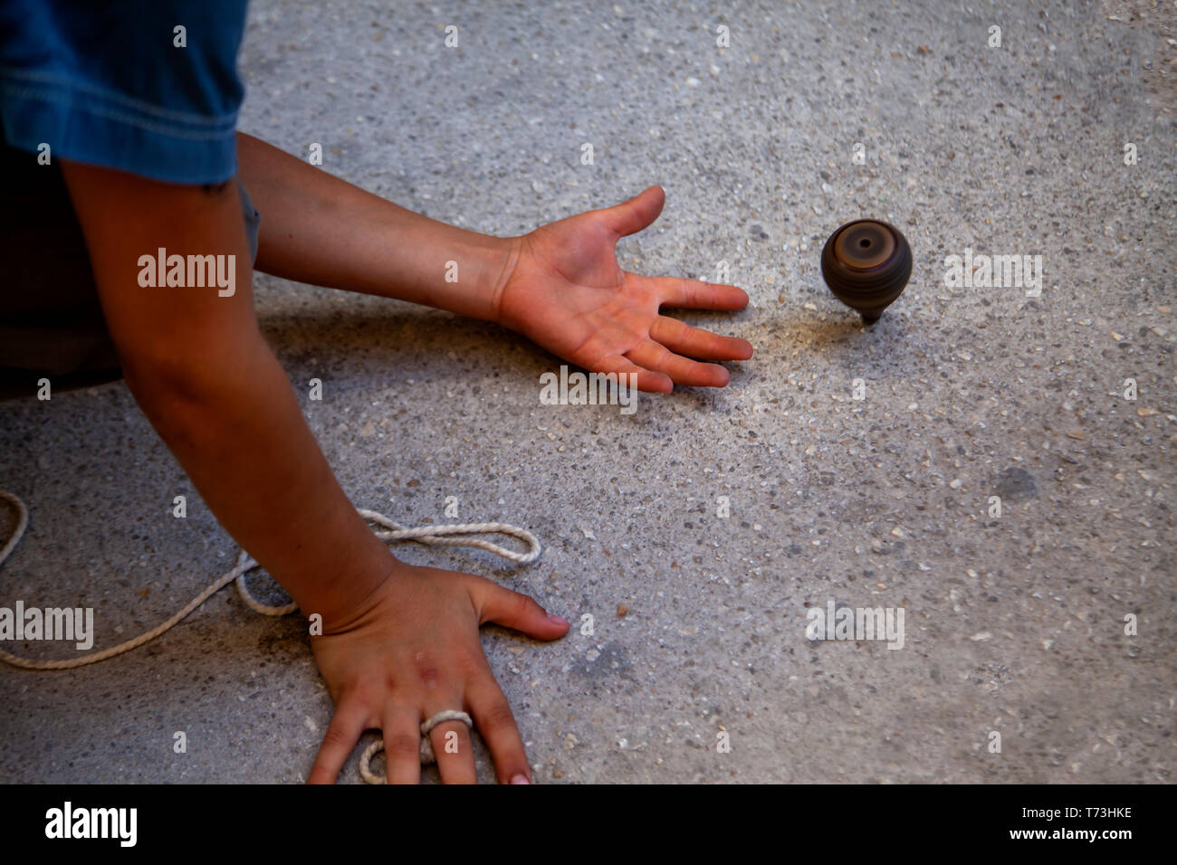 Ein Junge Rollen der String in einem hölzernen Kreisel auf der Straße. Alte türkische traditionelles Spielzeug. Stockfoto