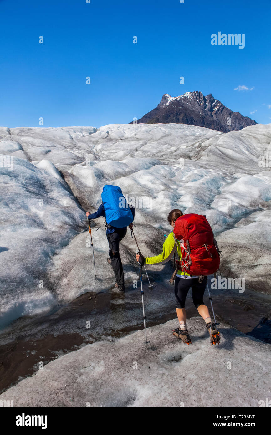 Ein Paar mit Rucksacktouren über den Root Glacier mit Steigeisen im Sommer in Richtung Donoho Peak, Wrangell Mountains, Wrangell-St. Elias-Nationalpark ... Stockfoto