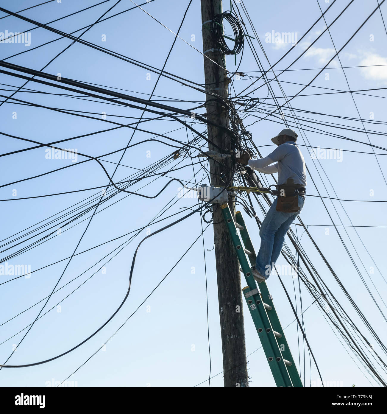 Elektriker Instandsetzung power line kabel auf eine Post, Französisch Hafen; Roatan, Bay Islands, Honduras Stockfoto