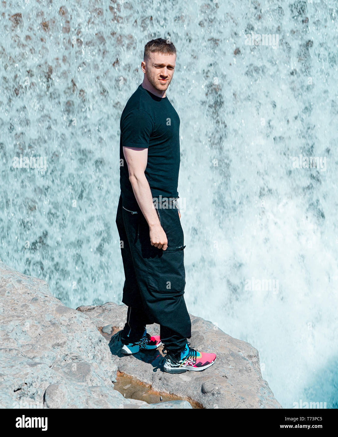 Jungen gutaussehenden Mann stand neben einem Wasserfall. Blogger und Reisende im Urlaub. Stockfoto