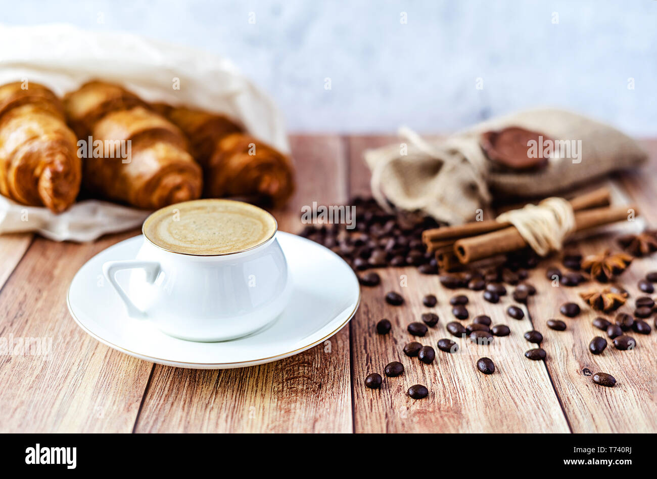 Perfektes Frühstück mit Croissants und Kaffee mit Milch auf hölzernen Tisch. Im rustikalen Stil. Close-up. Stockfoto