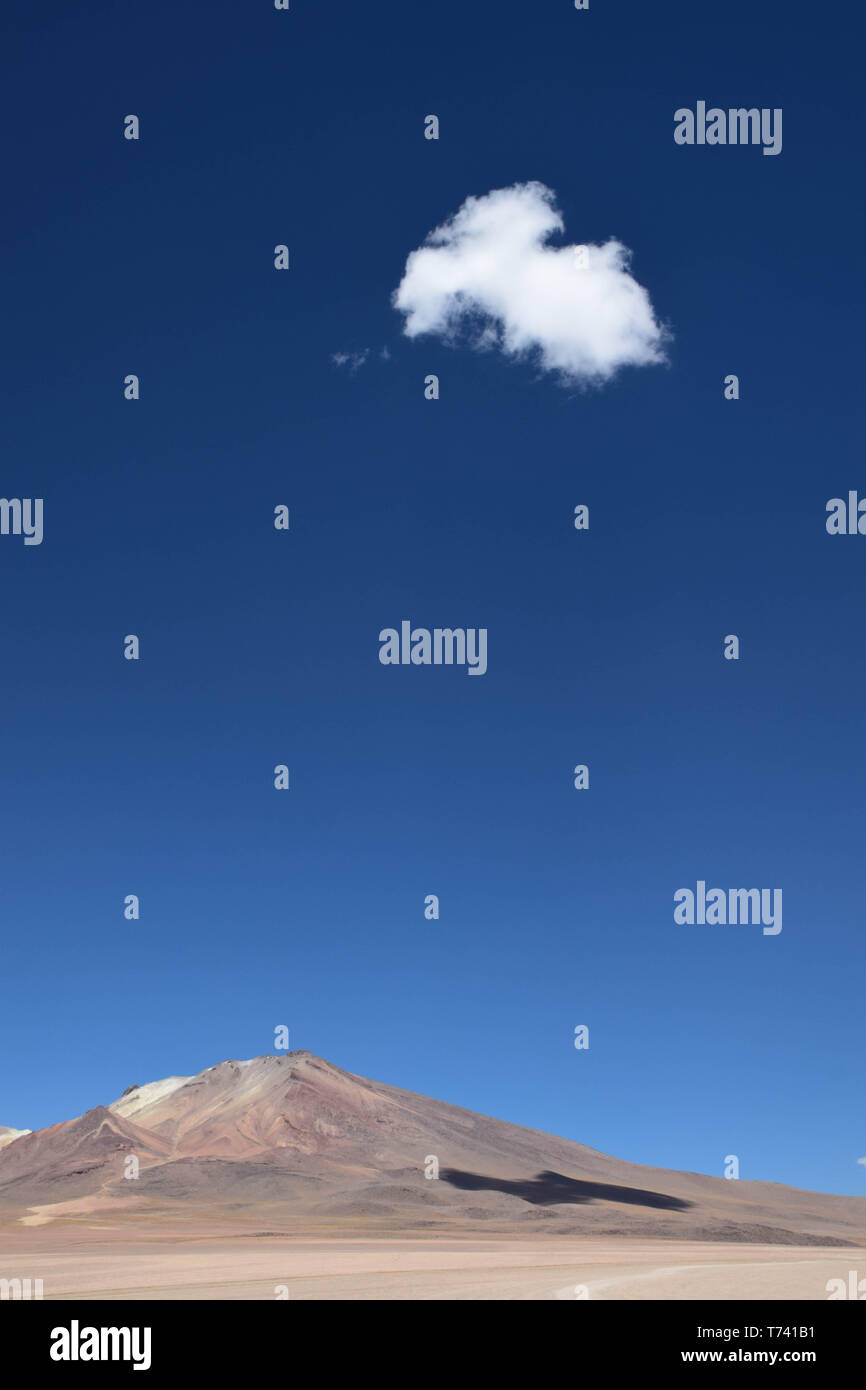 Eine einzige Wolke im klaren blauen Himmel, die auf einer Bergseite in der Landschaft des bolivianischen Hochlandes Schatten erzeugt. In der Nähe der wüste salvador dali in Th Stockfoto