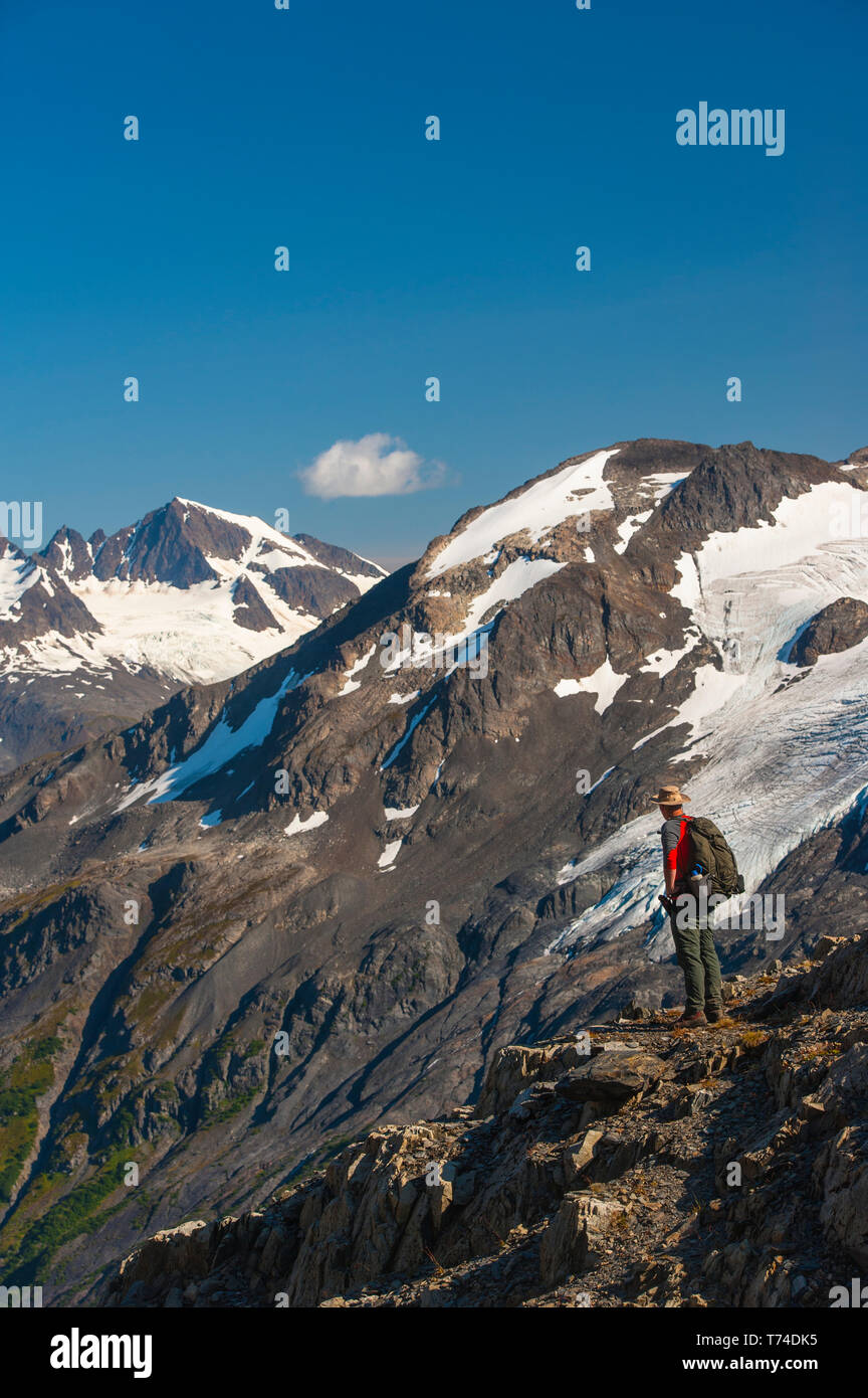 Der Kenai Fjords National Park, ein Mann, der in der Nähe des Harding Icefield Trail mit den Kenai Mountains und einem namenlosen hängenden Gletscher... Stockfoto