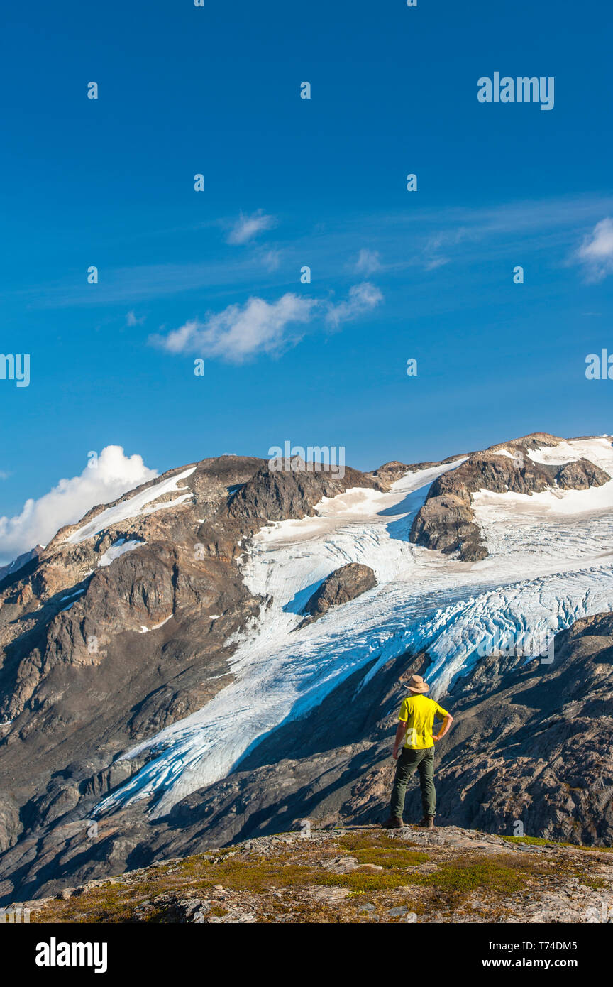 Der Kenai Fjords National Park, ein Mann, der in der Nähe des Harding Icefield Trail mit den Kenai Mountains und einem namenlosen hängenden Gletscher... Stockfoto