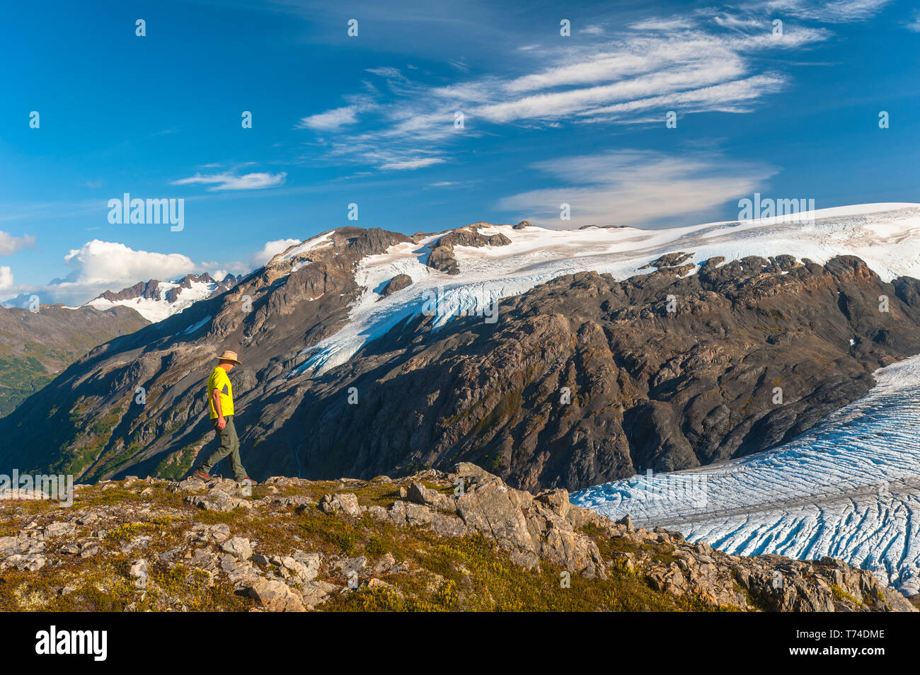 Der Kenai Fjords National Park, ein Mann, der in der Nähe des Harding Icefield Trail mit den Kenai Mountains und einem namenlosen hängenden Gletscher... Stockfoto