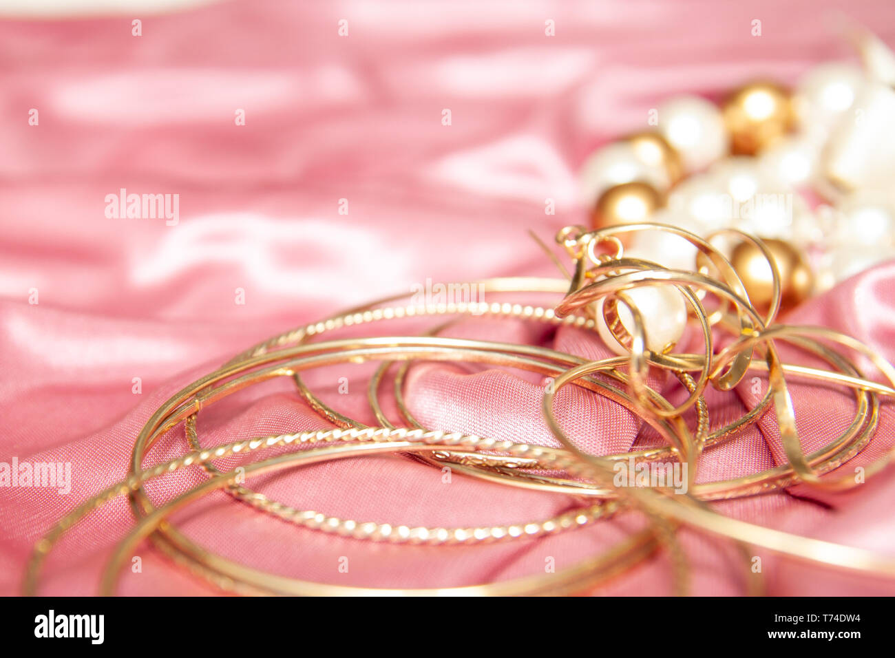 Schönheit Hintergrund mit Accessoires Schmuck, Armbänder, Ringe, Ohrringe auf rosa Textil. copyspase. Mode und Schönheit Konzept. Ansicht von oben flach Stockfoto