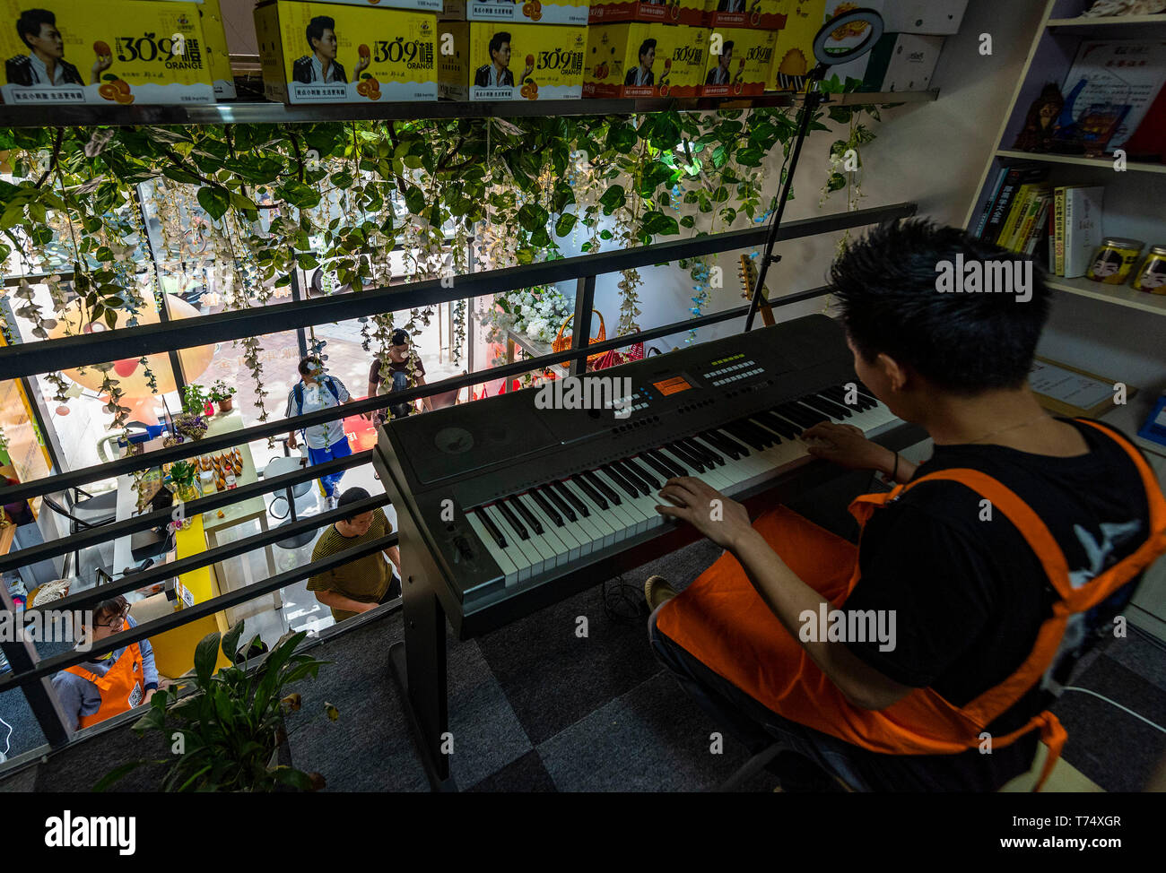 (190504) - YICHANG, 4. Mai 2019 (Xinhua) - Zheng Yunbo spielt elektronische Tastatur in einem neu eröffneten Obst store in Kunshan, China Provinz Hubei, 4. Mai 2019. Zheng Yunbo, 32, begann seine Karriere als obstbauer in seiner Heimatstadt Zigui County im Jahr 2012, wenn er verlassen, seinen Job in einer größeren Stadt mehrere Jahre nach ihrem Abschluss in Wuhan Konservatorium für Musik. Neben der Landwirtschaft, nahm er Vorteile der seine Spezialität durch das Hochladen von Musik videos auf soziale Netzwerke die Früchte, die er auf über 100 Mu (ca. 6,67 ha) von vermieteten Bereichen wuchs zu fördern. Die videos ging bald Viren im Internet und wo Stockfoto