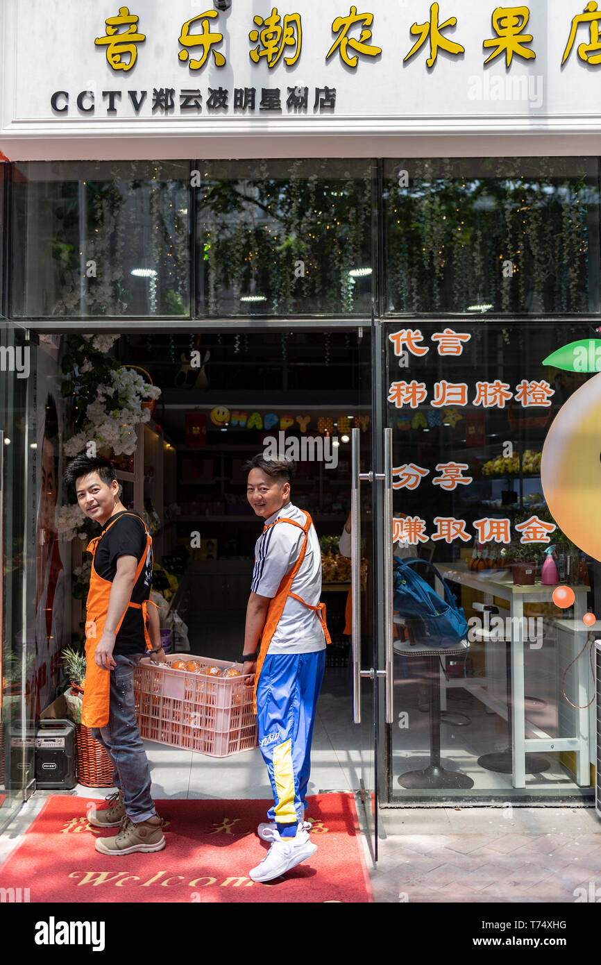 (190504) - YICHANG, 4. Mai 2019 (Xinhua) - Zheng Yunbo (L) und einem seiner Geschäftspartner Obst in einem neu eröffneten Obst lagern in Yichang, der Central China Provinz Hubei, 4. Mai 2019. Zheng Yunbo, 32, begann seine Karriere als obstbauer in seiner Heimatstadt Zigui County im Jahr 2012, wenn er verlassen, seinen Job in einer größeren Stadt mehrere Jahre nach ihrem Abschluss in Wuhan Konservatorium für Musik. Neben der Landwirtschaft, nahm er Vorteile der seine Spezialität durch das Hochladen von Musik videos auf soziale Netzwerke die Früchte, die er auf über 100 Mu (ca. 6,67 ha) von vermieteten Bereichen wuchs zu fördern. Die videos ging bald virale Stockfoto