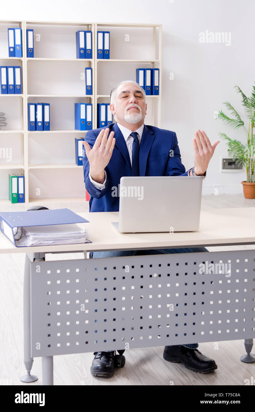 Alter Geschäftsmann Yoga Übungen im Büro Stockfoto