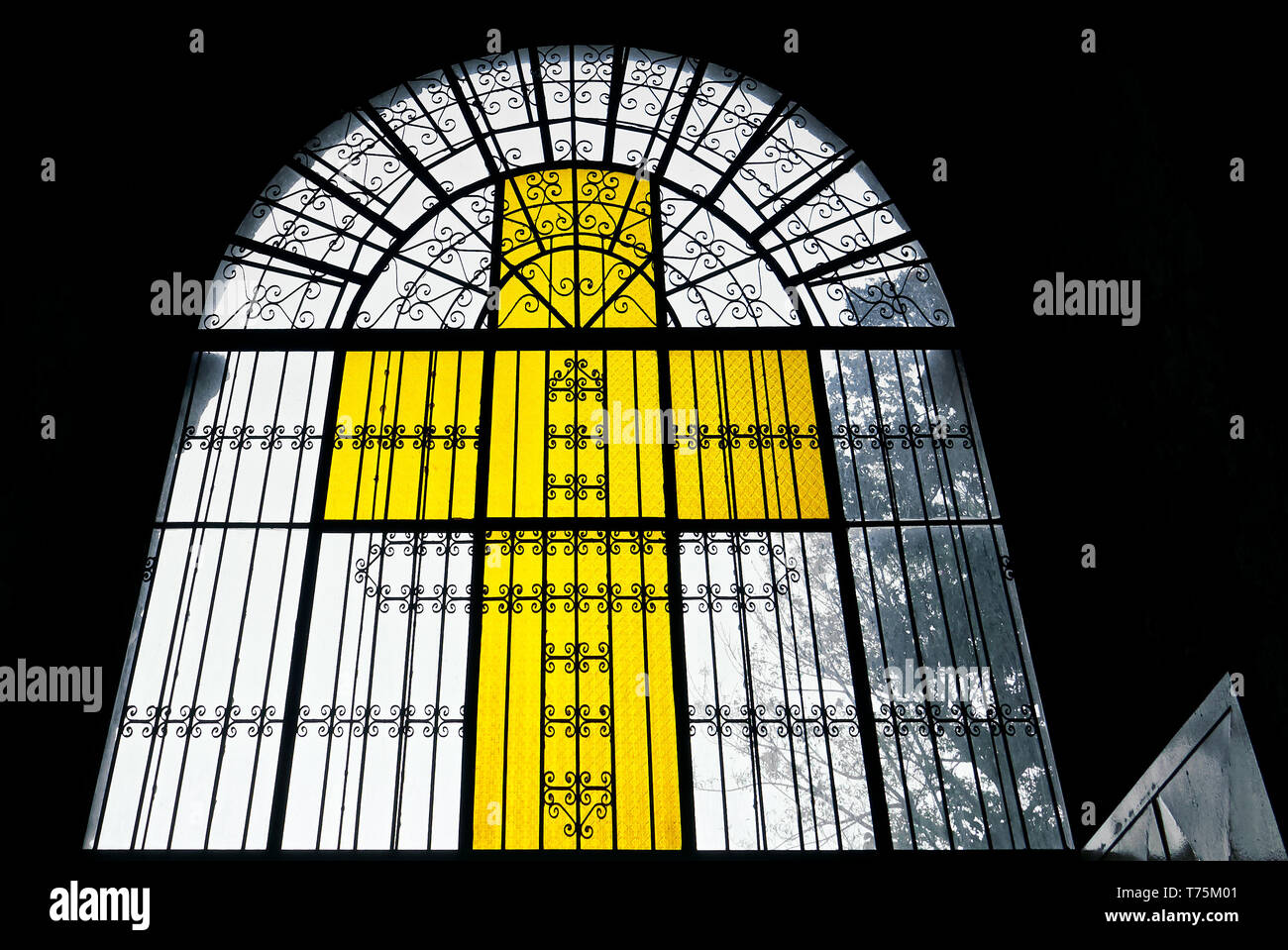 Licht durch eine gelb gefärbte Kreuzes Fenster aus buntem Glas und Metall Werke der Kirche in Leon Stadt scheint, Provinz Iloilo, Philippinen Stockfoto