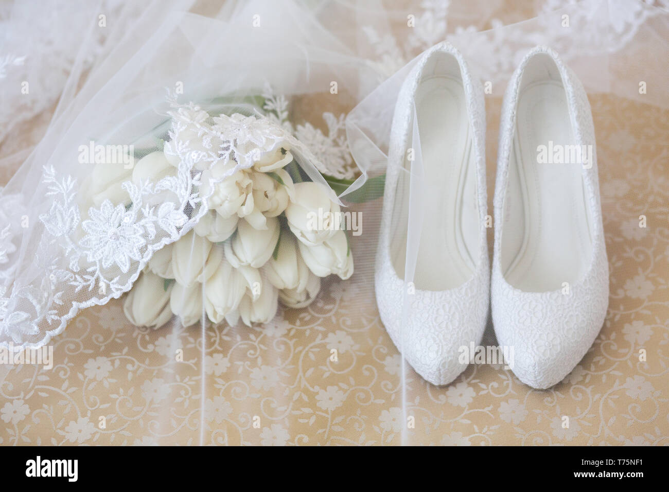 Wedding Bouquet von weißen Tulpen mit einem Schleier Neben weißen High Heel Schuhe der Braut abgedeckt Stockfoto