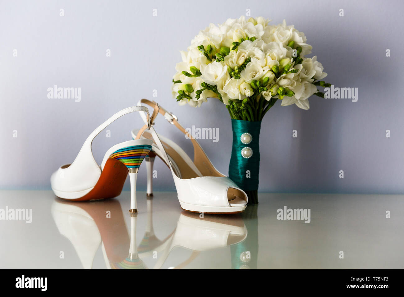 Brautstrauß aus weißen Freesien, mit Satinband auf dem Hintergrund der High Heel Schuhe der Braut eingerichtet Stockfoto
