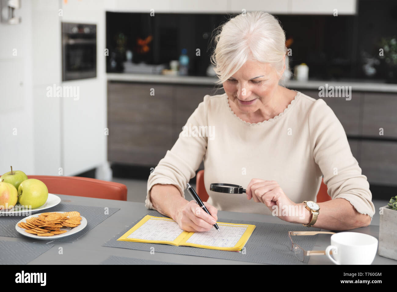 Ältere Frau genießt das Lösen eines Kreuzworträtsels zu Hause Stockfoto