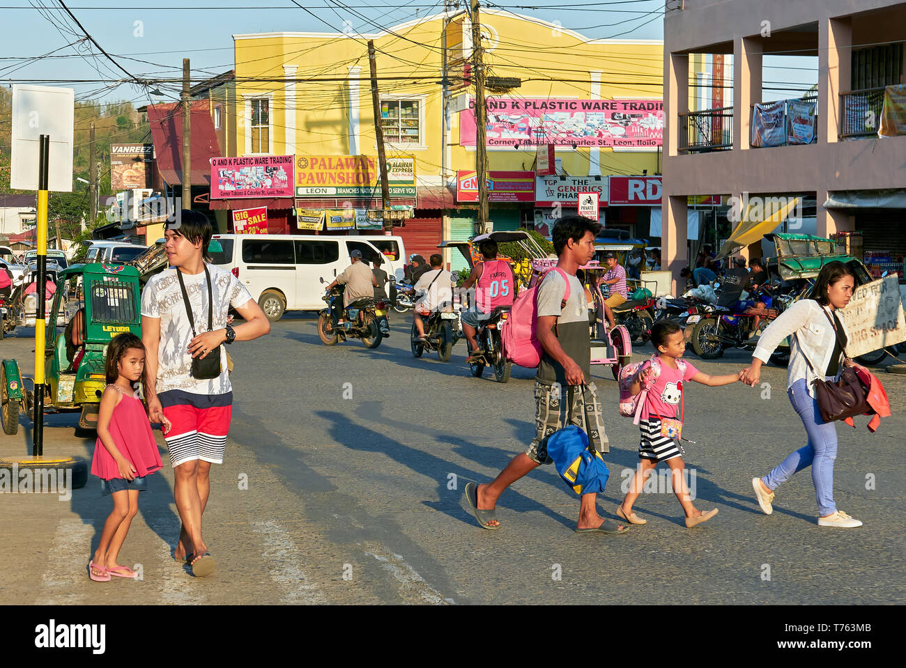 Leon, Provinz Iloilo, Philippinen - April 18, 2019: Junge Eltern mit ihren Kindern zu Fuß auf den Straßen während der Nachmittag der Verkehr Stockfoto