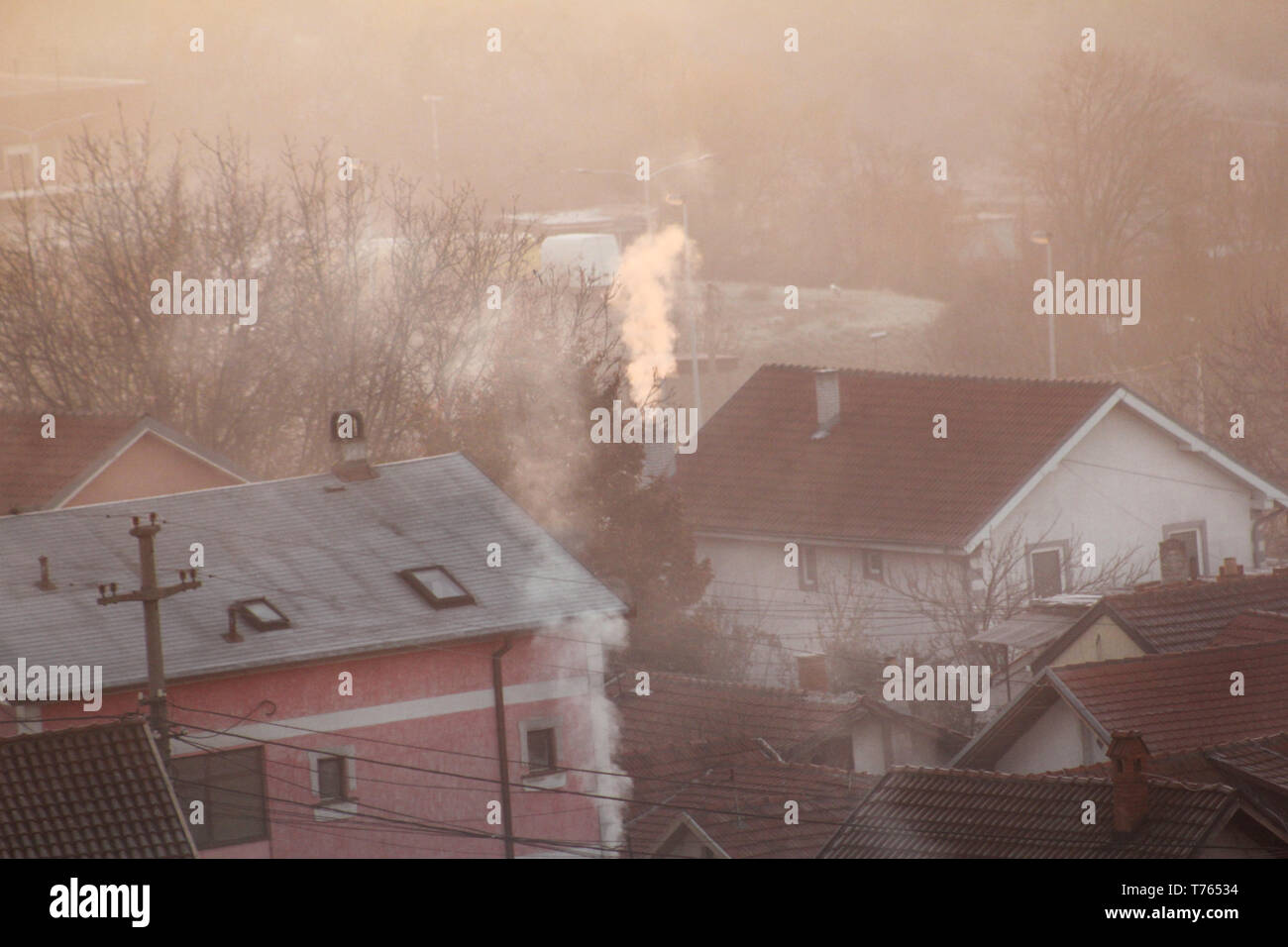 Rauchende Schlote auf Dächer der Häuser gibt Rauch, Smog bei Sonnenaufgang, Schadstoffe geben Sie Atmosphäre. Umweltkatastrophe. Schädliche Emissionen und Abgase. Stockfoto