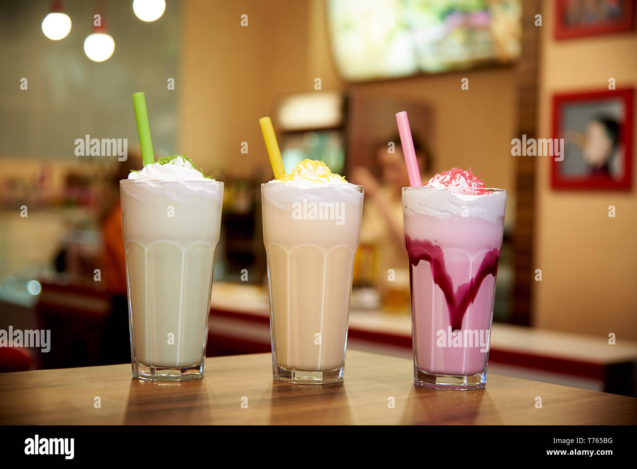 Milchshakes mit Strohhalmen auf einem hölzernen Tisch in einem Cafe. Stockfoto