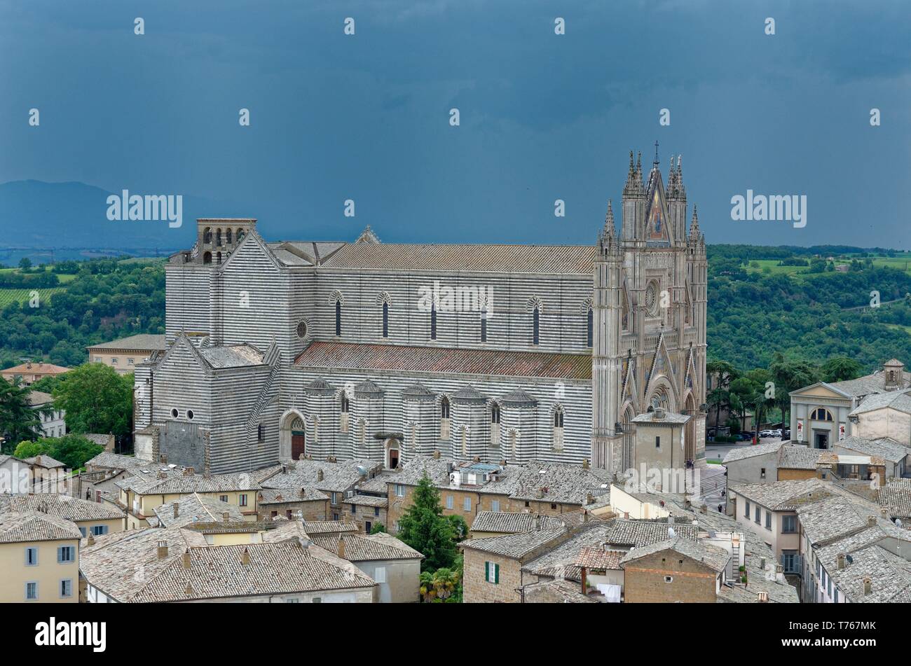 Über die Dächer nach Orvieto Kathedrale (Duomo di Orvieto) im Sonnenlicht, bevor die dunklen grauen Himmel eines herannahenden Sturm, vom Uhrenturm gesehen Stockfoto