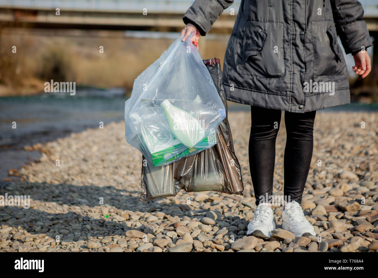 Müll in der Natur, in der die Reinigung der Umgebung im Frühjahr auf dem Fluss vom Müll eine Frau in Latex Handschuhe Blau in Blau, groß Stockfoto