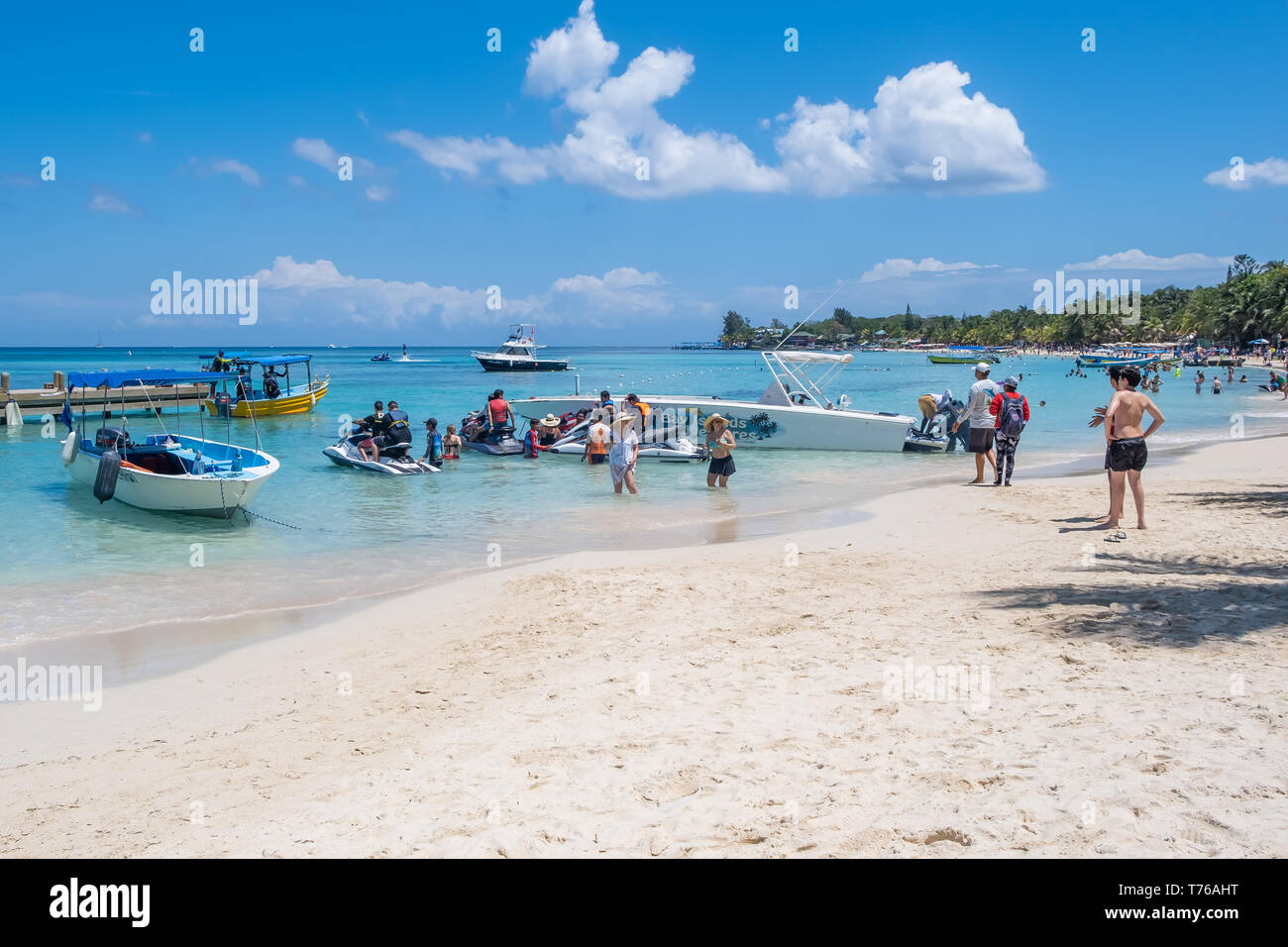 Die Menschen genießen den schönen Strand von West Bay Roatan Honduras auf einem perfekten sonnigen Tag. Stockfoto