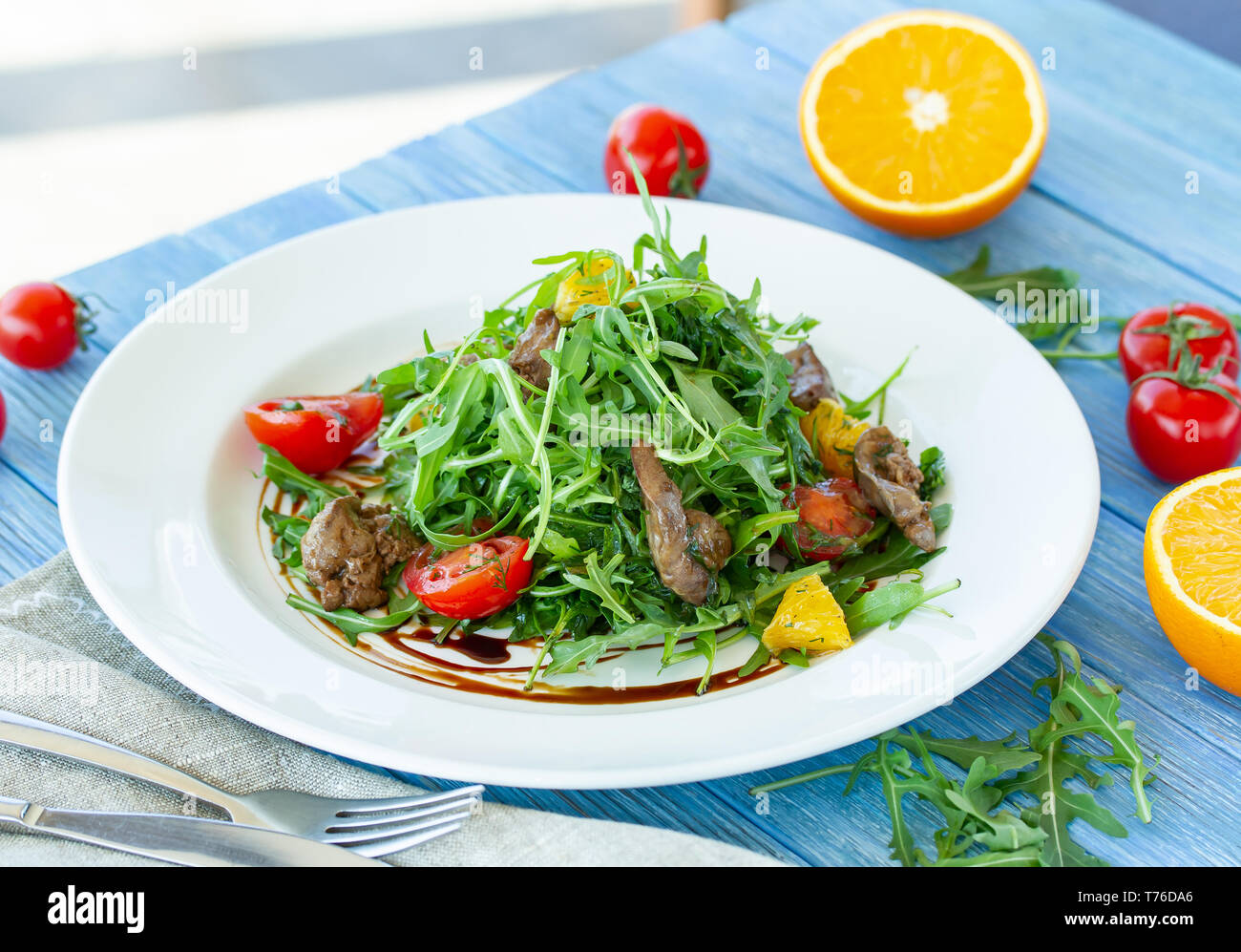 Salat mit Huhn Leber, Rucola, Orangen und Tomaten auf einer Platte an einem sonnigen Tag Stockfoto