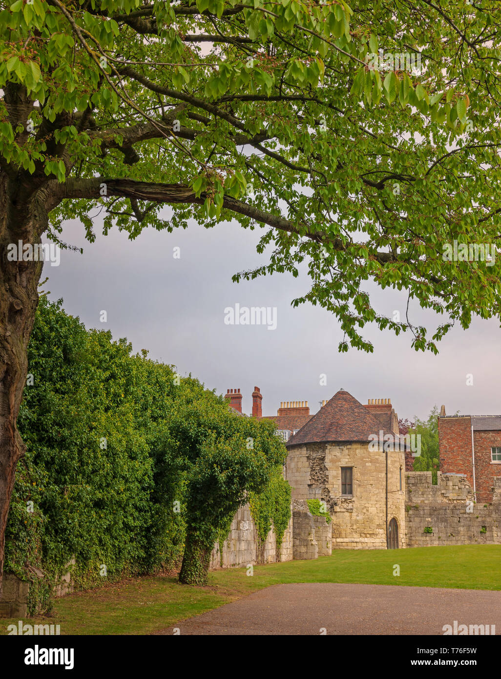 Alte runde Turm in Stadtmauern von York. Die Häuser sind auf der anderen Seite und Es ist ein bewölkter Himmel oben. Stockfoto