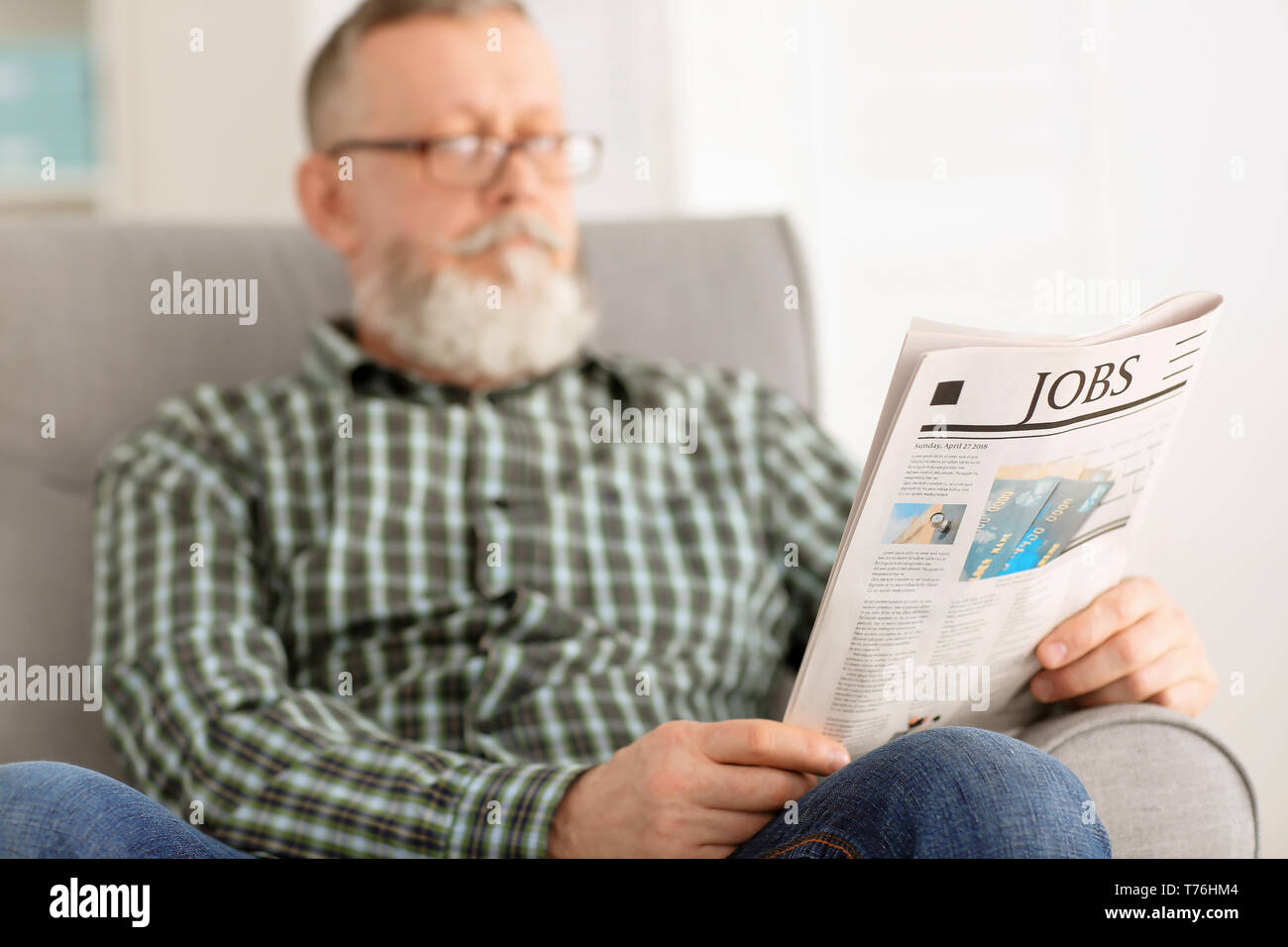 Ältere Mann liest Zeitung zu Hause Stockfoto
