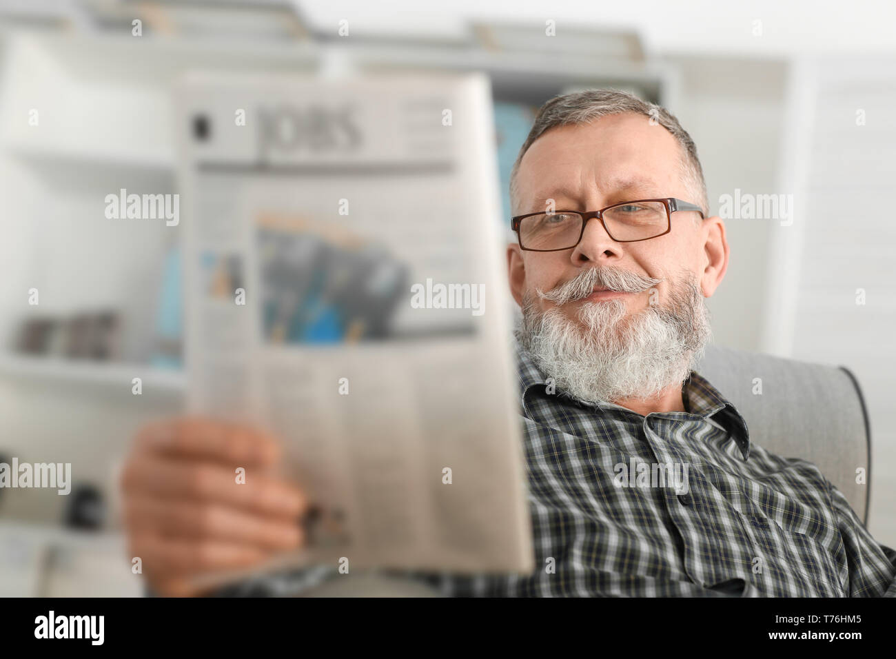 Ältere Mann liest Zeitung zu Hause Stockfoto