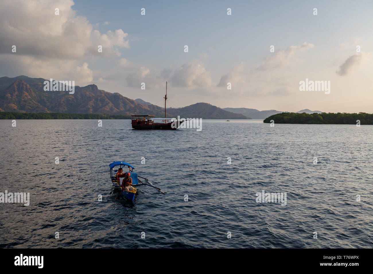 Zwei Leute, die sich für native Outrigger Kanu fahren Sie in Richtung Ufer. Traditionelles Segelschiff im Hafen Stockfoto