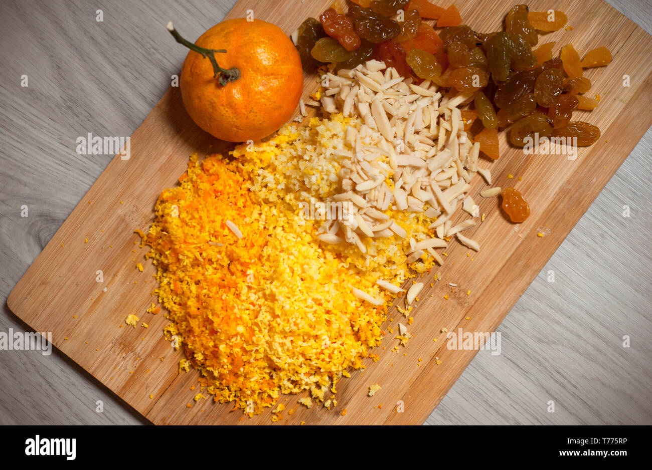 Getrocknete Rosinen, Mandeln und zerdrückten mandarin Muscheln auf Holzbrett über graues Holz- Hintergrund, Ansicht von oben. Close-up. Stockfoto