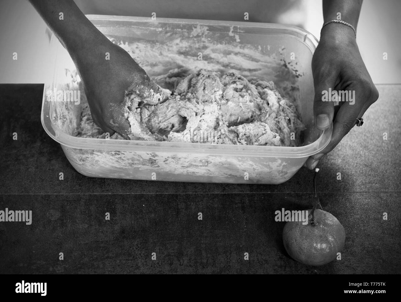 Frau macht Teig für Ostern Kuchen mit getrockneten Rosinen, Mandeln und zerdrückten mandarin Schalen über braun Holz- Hintergrund. Close-up von Doug, Stockfoto