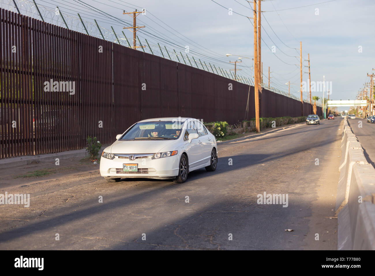 MEXICALI, MEXIKO - 8 April ein Auto fährt von der US-mexikanischen Grenze Mauer April 8, 2019 in Mexicali, Mexiko. Unter den Gebäuden des Zentrums von Mexicali Stockfoto