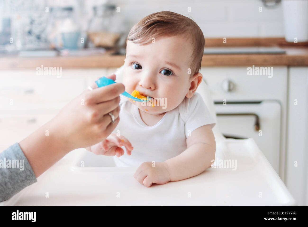 Charmantes kleines Baby Boy 6-8 Monate essen zunächst Essen Kürbis vom Löffel zu Hause Stockfoto