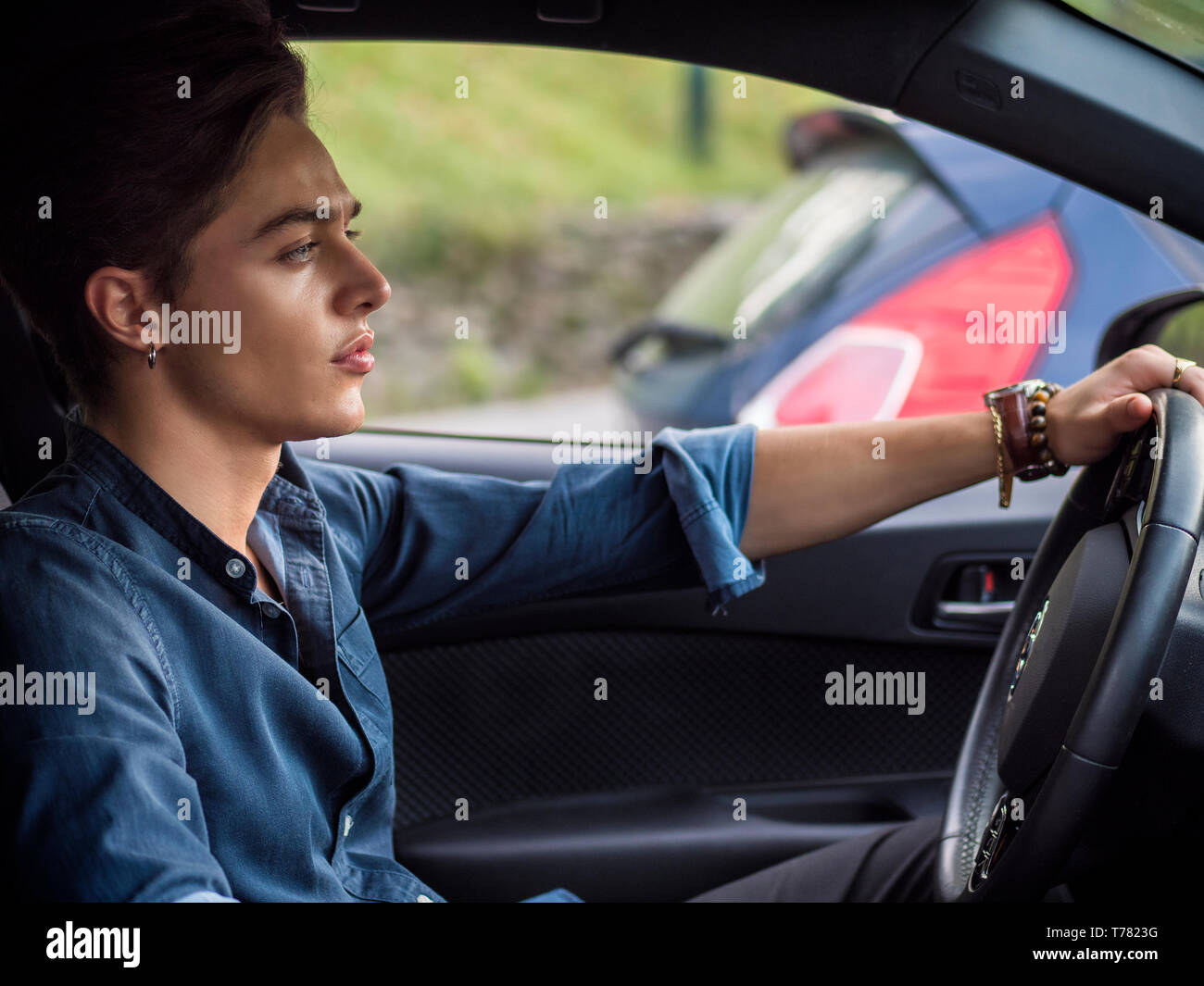 Hübscher junger Mann, der in seinem Auto sitzt und wegschaut Stockfoto