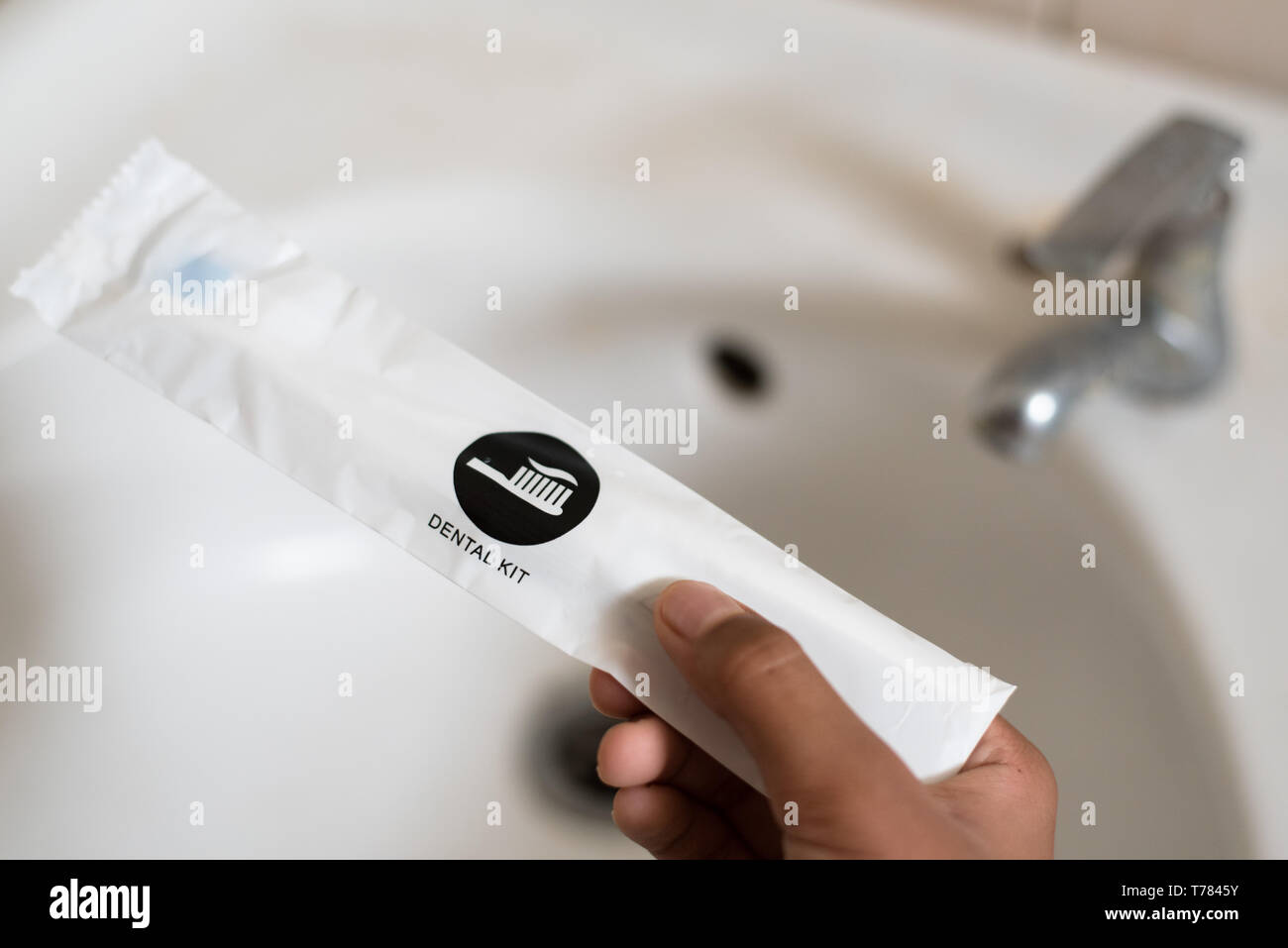 Hand mit einem zahnmedizinischen Kit gegen WC Waschbecken gesetzt. Konzept der Zahnpflege, Hygiene und Reisen Stockfoto