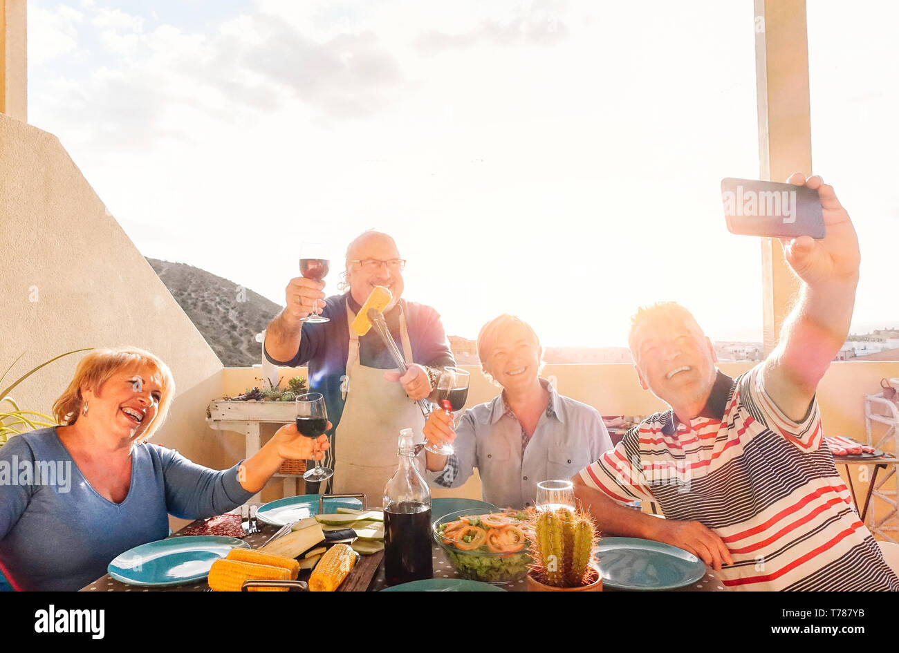 Happy Senioren einen selfie mit Handy und ein Barbecue auf der Dachterrasse - Rentner spaß essen und trinken Rotwein Stockfoto