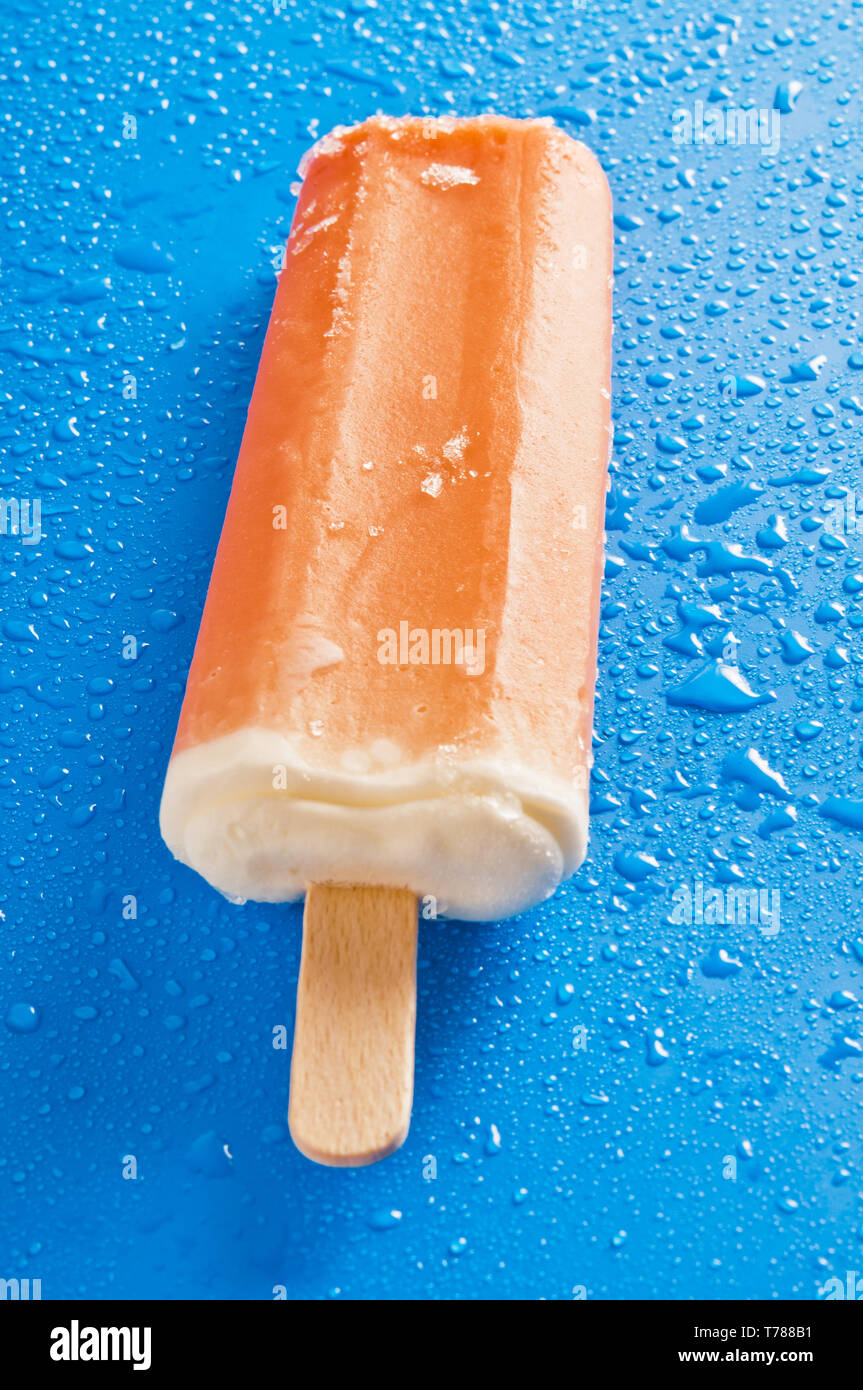 Orange Eis am Stiel oder Eis pop auf einem blauen Hintergrund mit  Wassertropfen Stockfotografie - Alamy