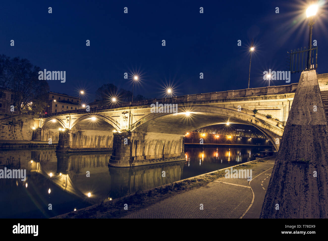 Ponte Sisto ist eine steinerne Straßenbrücke in der Altstadt von Rom über den Tiber in der Nacht mit Beleuchtung. Pfad am Ufer mit seitlichem Stockfoto