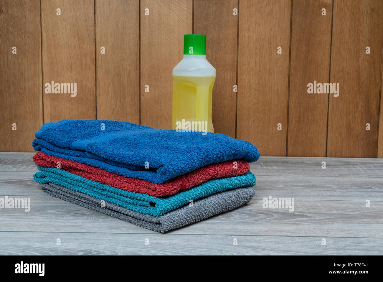 Gebügelte Bettwäsche und eine Flasche Reinigungsmittel auf dem Tisch Stockfoto