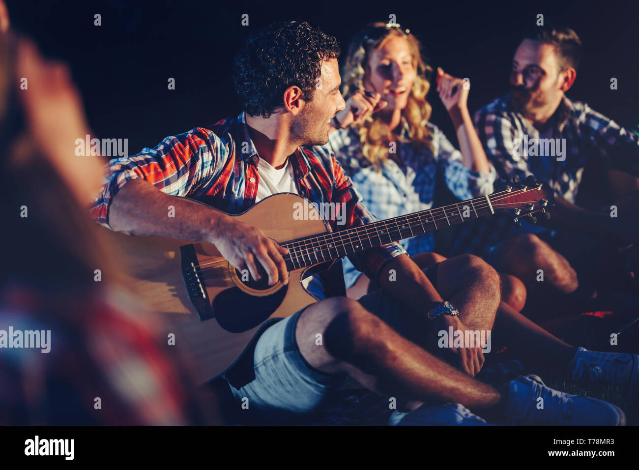 Genießen Sie Musik in der Nähe von Lagerfeuer am Abend Freunde Stockfoto