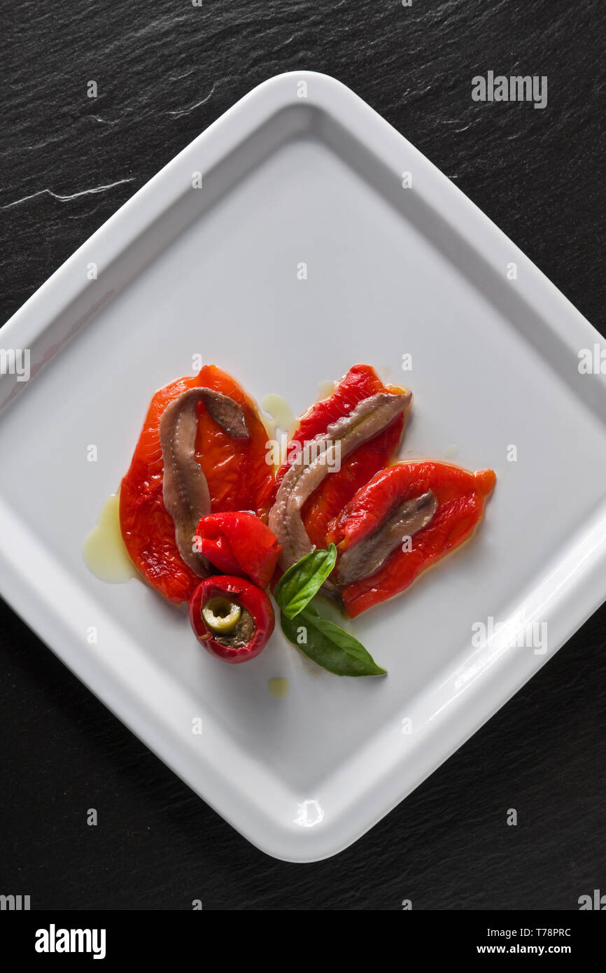 Un piatto con alici (acciughe) e Peperoni guarniti da basilico. [ENG] eine Platte mit Sardellen und Paprika, mit Basilikum. Stockfoto