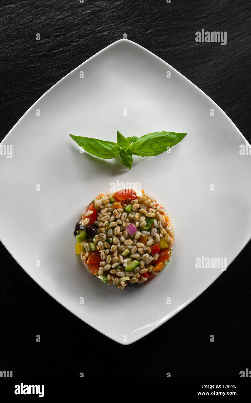 Piatto di Insalata di farro con Pomodori, basilico e olive. [ENG] ein Teller Salat Dinkel mit Tomaten, Basilikum und Oliven. Stockfoto