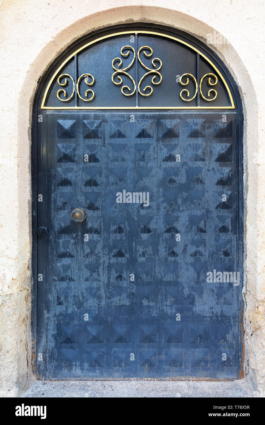 Eine alte eiserne Tür mit einem verblichenen Stone Arch, ein Metallic gold Rahmen und einem schmiedeeisernen sperren Stockfoto